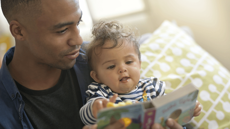A father reading to an infant.