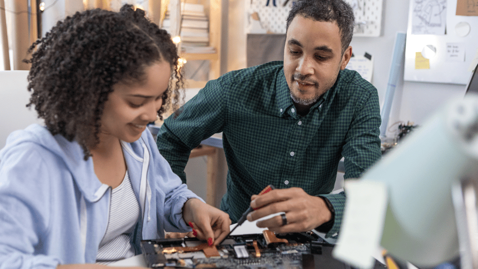 A father and daughter work together to rebuild a motherboard on a computer. 