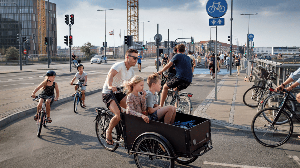 A happy dad and his children biking through the streets together.