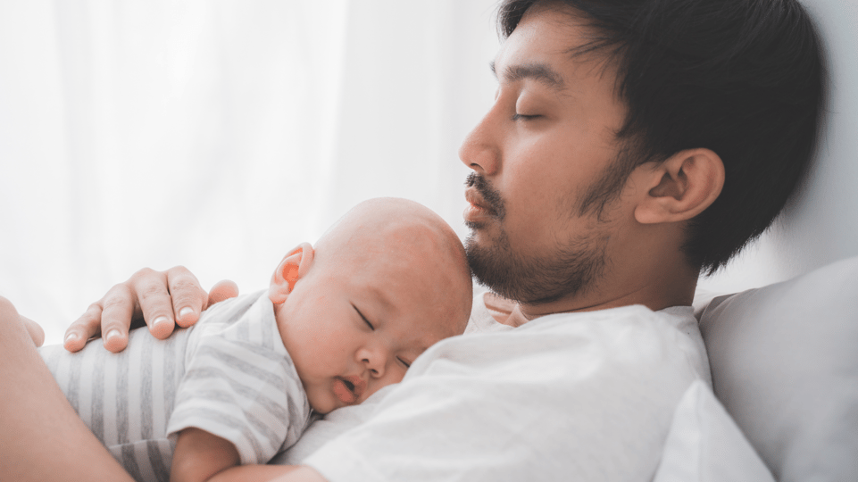 A sleeping dad with his infant asleep on his chest.